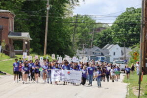 Hundreds of students participate in the third annual Burlington Community Walk to Fight Suicide while holding signs promoting mental health.