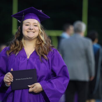 A graduate proudly displays her diploma after walking across the stage at the 2024 Commencement Ceremony at Bracewell Stadium.