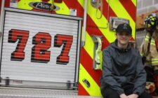 Christian Teeter, a 14-year-old eighth grade student at Edward Stone Middle School, sits on the back of Engine 727 April 26 at the Burlington Fire Department just before leaving on a call.