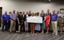 Representatives for Molina Healthcare, iJAG, Burlington High School and BCSD pose for a photo while holding up a giant check in the amount of $25,000 from Molina Cares to iJAG.