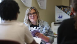 A paraeducator reads along to a book with a group of students